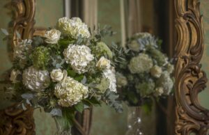 Contact us to enquire about the tall white hydrangea and rose table centrepiece full of foliage texture and photographed in front of a mirror at Thirlestane Castle